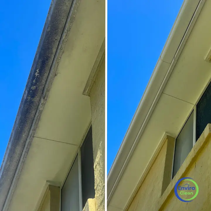 Eaves and fascia against a blue sky, before and after a house wash: dark mould on the left, clean on the right.
